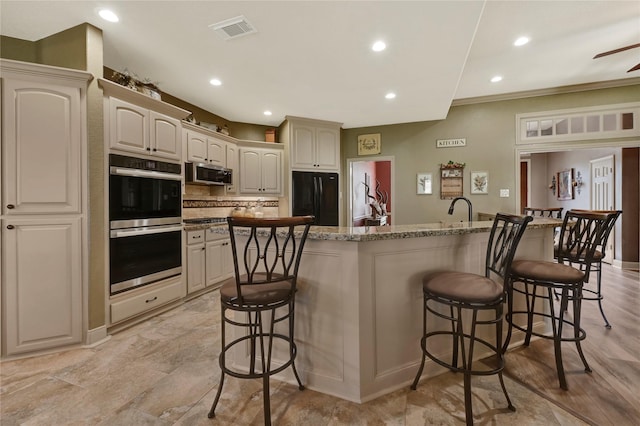 kitchen with tasteful backsplash, appliances with stainless steel finishes, a breakfast bar area, and a center island with sink