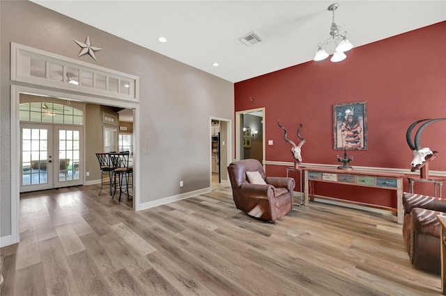 living area featuring an inviting chandelier, light hardwood / wood-style flooring, and french doors