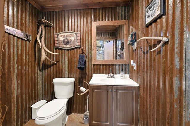 bathroom with vanity, wooden walls, and toilet