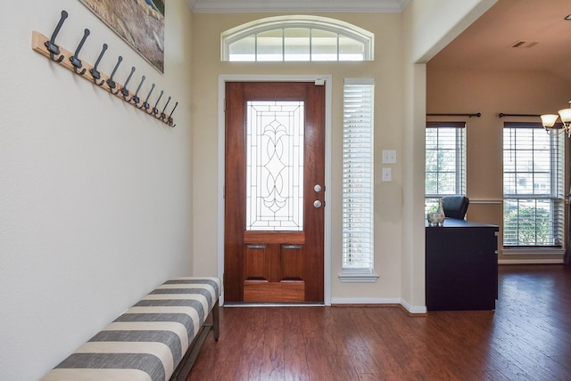 entryway featuring dark wood-type flooring, ornamental molding, and a chandelier