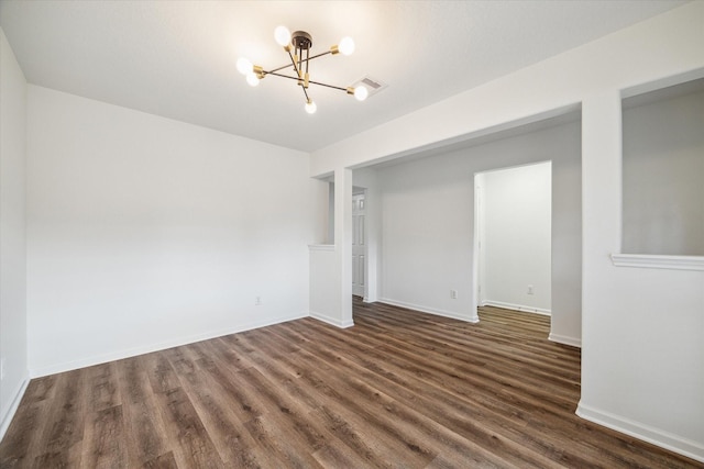 unfurnished room with a notable chandelier and dark hardwood / wood-style floors