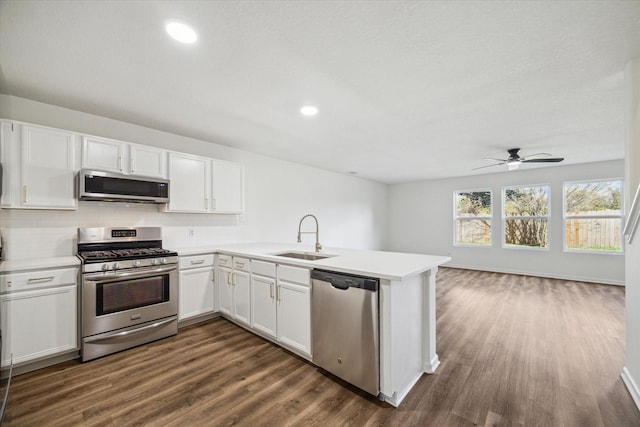 kitchen featuring sink, white cabinets, dark hardwood / wood-style flooring, kitchen peninsula, and stainless steel appliances