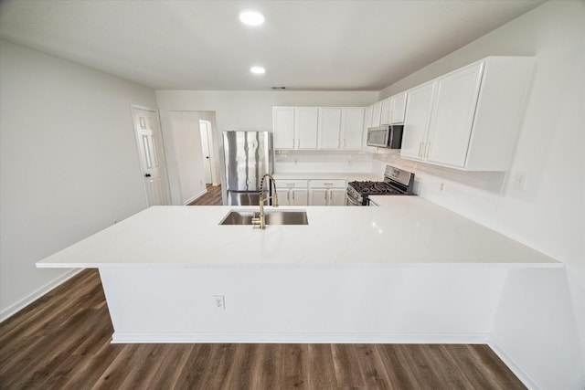 kitchen featuring sink, white cabinetry, dark hardwood / wood-style floors, kitchen peninsula, and stainless steel appliances