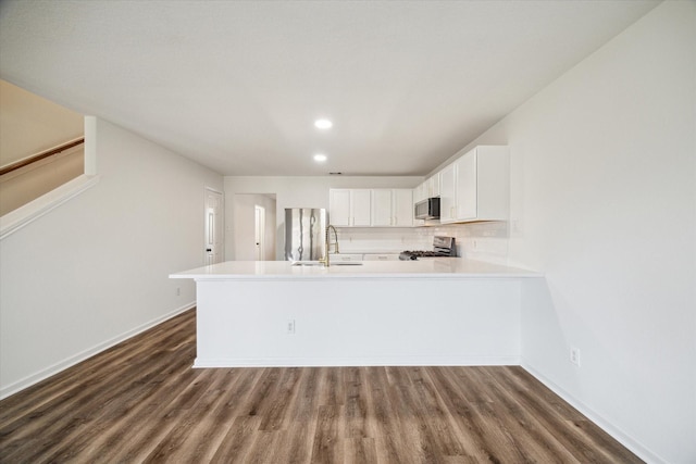 kitchen with dark hardwood / wood-style floors, stainless steel appliances, kitchen peninsula, and white cabinets