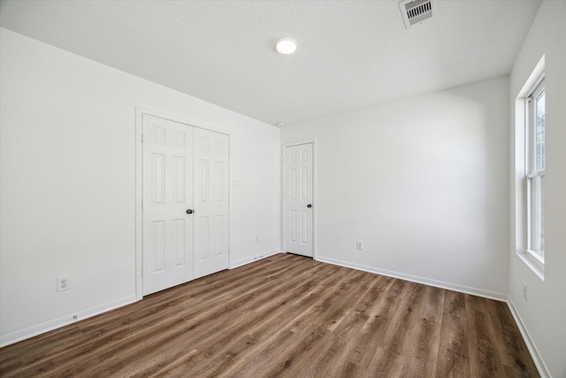 unfurnished bedroom with dark hardwood / wood-style floors and a closet