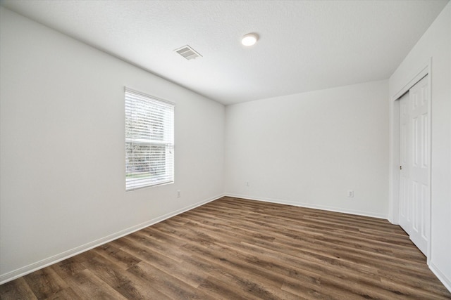 unfurnished bedroom with a closet and dark hardwood / wood-style floors