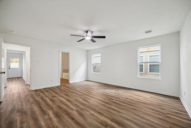 unfurnished room with a healthy amount of sunlight, dark hardwood / wood-style floors, and ceiling fan