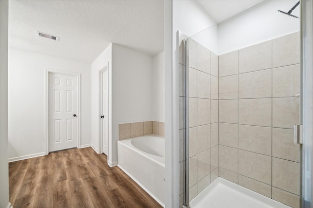 bathroom with hardwood / wood-style flooring, independent shower and bath, and a textured ceiling