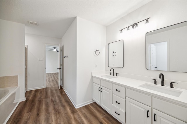 bathroom featuring vanity, a bath, hardwood / wood-style floors, and a textured ceiling