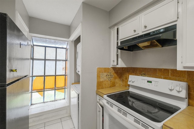 kitchen with tasteful backsplash, white cabinets, stacked washer and dryer, electric range, and black fridge