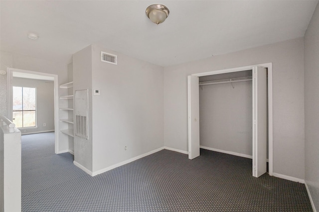 unfurnished bedroom featuring dark carpet and a closet