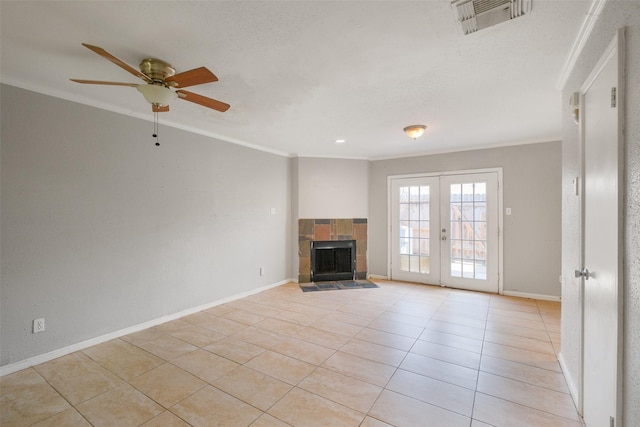 unfurnished living room featuring french doors, ornamental molding, a tiled fireplace, and light tile patterned floors