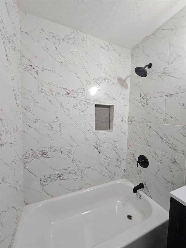 bathroom featuring vanity, tiled shower / bath combo, and a textured ceiling