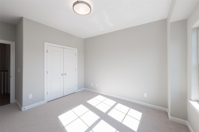 unfurnished bedroom featuring a closet and light carpet