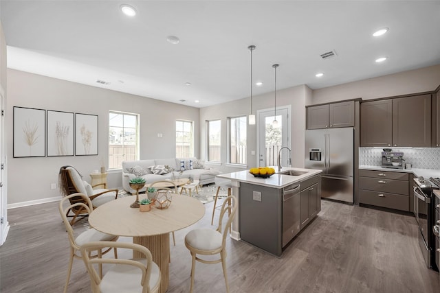 kitchen with pendant lighting, sink, appliances with stainless steel finishes, a kitchen island with sink, and dark hardwood / wood-style floors