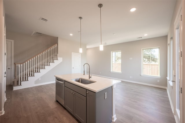 kitchen with sink, gray cabinetry, decorative light fixtures, stainless steel dishwasher, and a kitchen island with sink