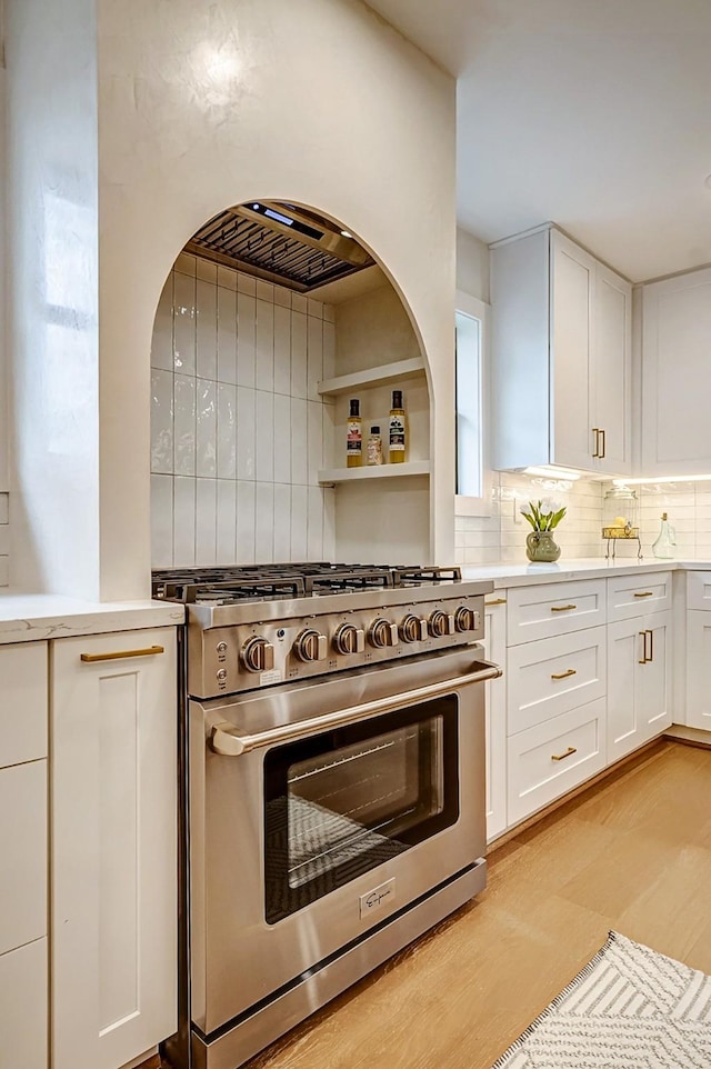 kitchen with high end range, white cabinetry, and decorative backsplash