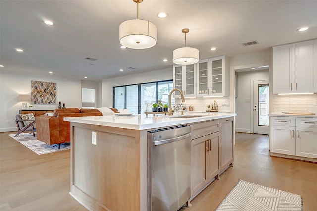 kitchen featuring white cabinetry, stainless steel dishwasher, hanging light fixtures, and a center island with sink