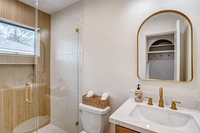 bathroom with vanity, a shower with door, and toilet