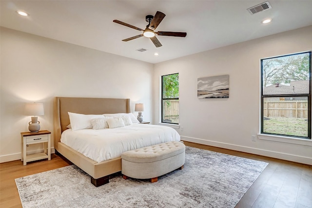 bedroom with multiple windows, hardwood / wood-style floors, and ceiling fan