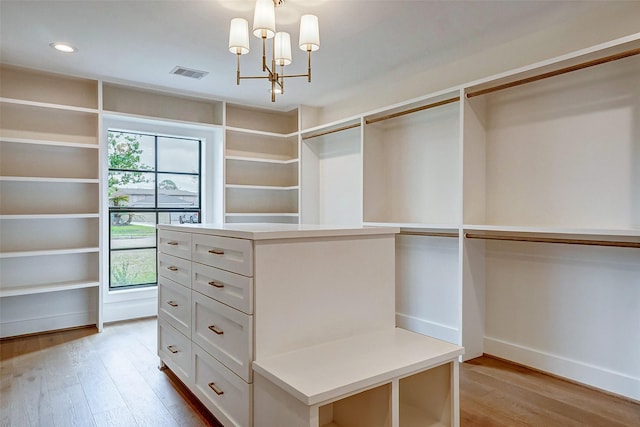 spacious closet with an inviting chandelier and light hardwood / wood-style floors