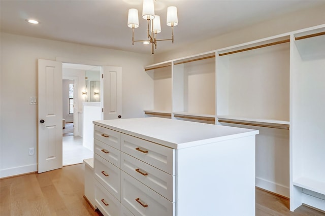 walk in closet featuring light hardwood / wood-style floors and a chandelier