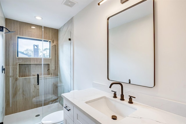 bathroom featuring vanity, toilet, and a shower with door