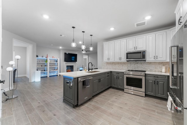 kitchen featuring white cabinetry, appliances with stainless steel finishes, gray cabinets, kitchen peninsula, and pendant lighting