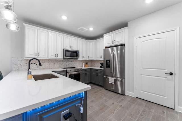 kitchen featuring high end appliances, white cabinetry, sink, and hanging light fixtures