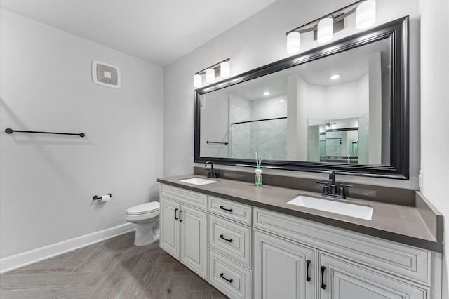 bathroom featuring toilet, vanity, and a shower with shower door