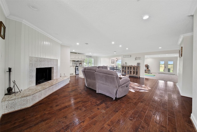 living room with a high end fireplace, dark wood-type flooring, ornamental molding, and a textured ceiling