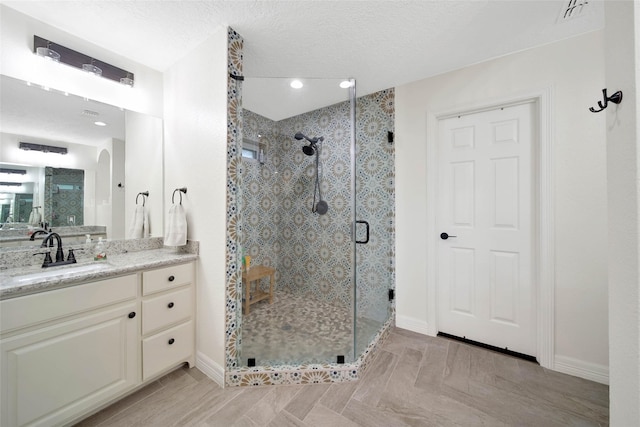 bathroom with an enclosed shower, vanity, and a textured ceiling