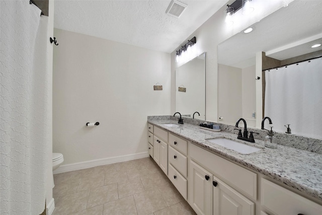 bathroom with vanity, tile patterned flooring, a textured ceiling, and toilet