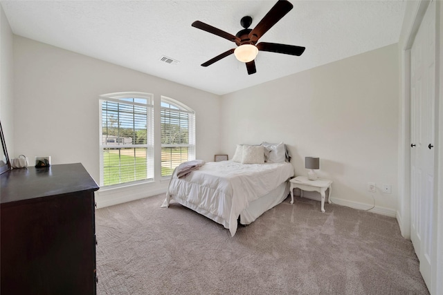 carpeted bedroom featuring ceiling fan and a textured ceiling