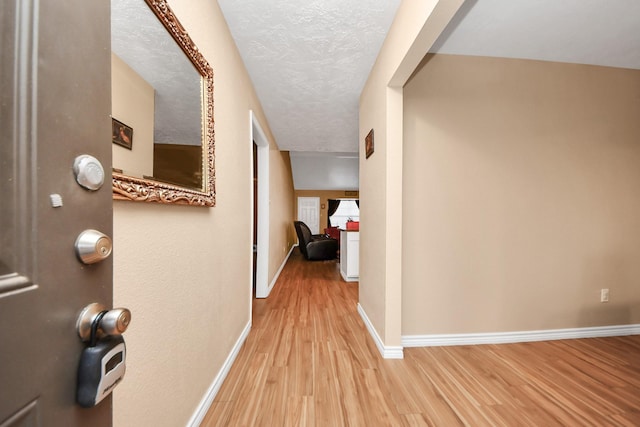 corridor with light hardwood / wood-style floors and a textured ceiling