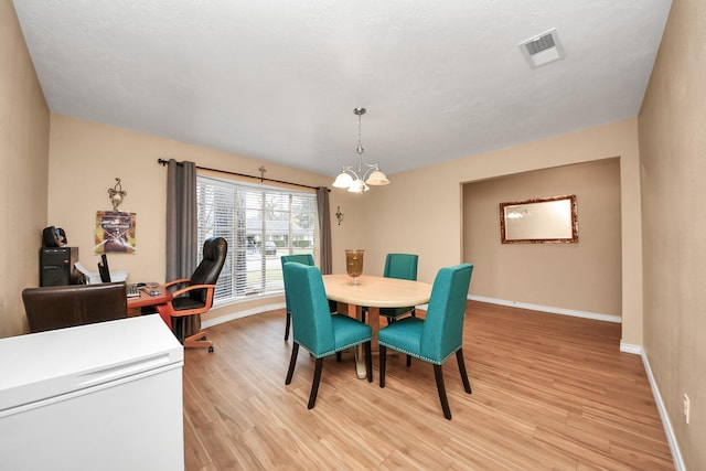 dining area featuring a notable chandelier and light hardwood / wood-style floors