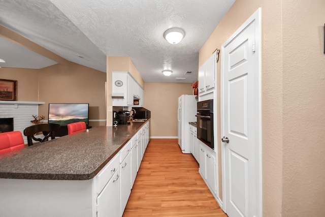 kitchen featuring white cabinetry, oven, kitchen peninsula, and white refrigerator