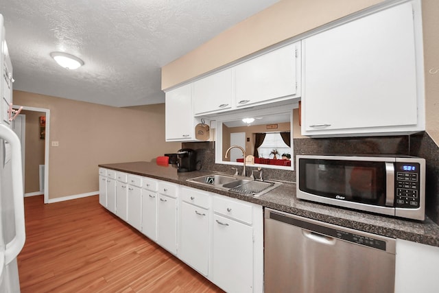 kitchen featuring light wood-type flooring, appliances with stainless steel finishes, sink, and white cabinets