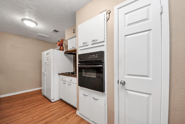 kitchen featuring light hardwood / wood-style flooring, black oven, white fridge with ice dispenser, a textured ceiling, and white cabinets