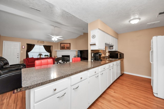 kitchen with sink, lofted ceiling with beams, white refrigerator, kitchen peninsula, and white cabinets