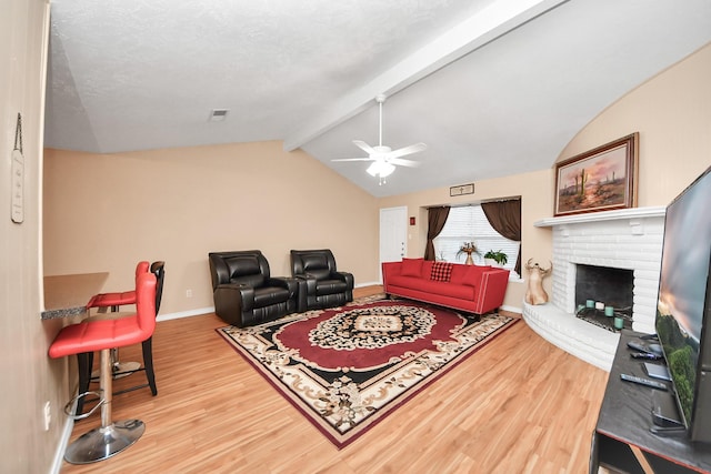 living room featuring lofted ceiling with beams, wood-type flooring, ceiling fan, and a fireplace