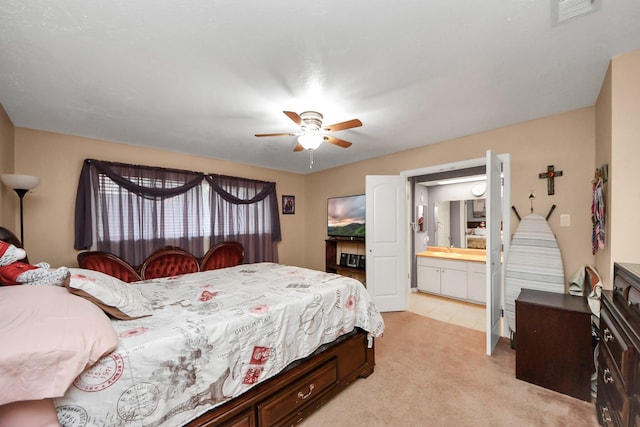 bedroom with ceiling fan, light colored carpet, sink, and ensuite bath