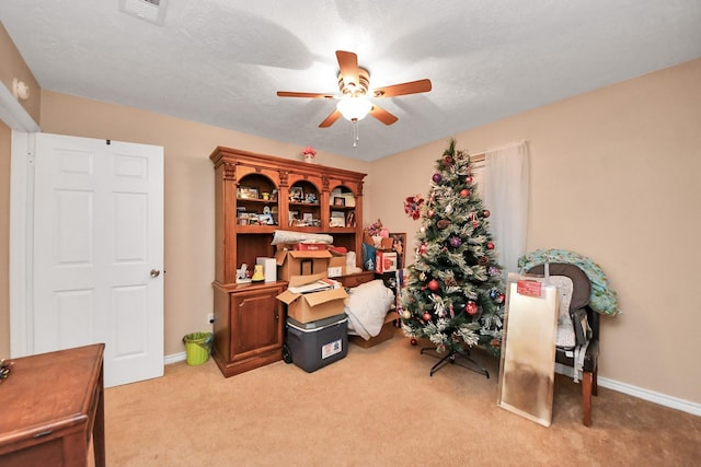 home office featuring ceiling fan, light carpet, and a textured ceiling