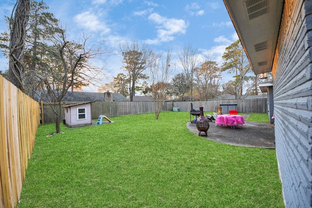 view of yard featuring a shed, a patio area, and an outdoor fire pit