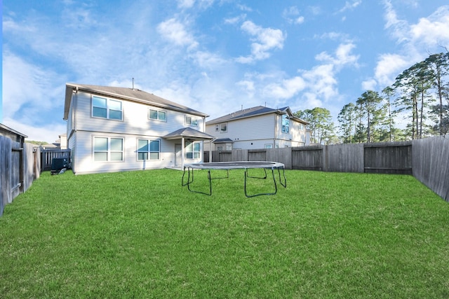 rear view of house featuring a yard and a trampoline