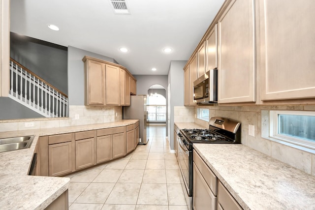 kitchen with tasteful backsplash, light tile patterned floors, stainless steel appliances, and light brown cabinetry