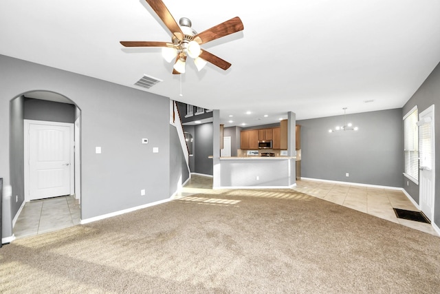 unfurnished living room with ceiling fan with notable chandelier and light carpet