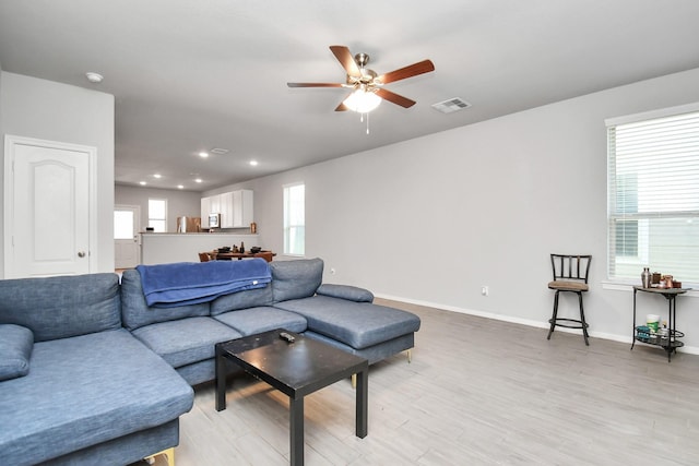 living room with ceiling fan, plenty of natural light, and light wood-type flooring