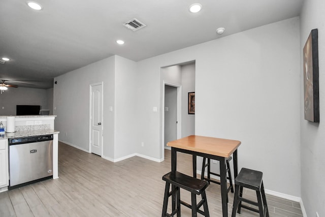 kitchen featuring light stone counters, light hardwood / wood-style flooring, dishwasher, ceiling fan, and white cabinets