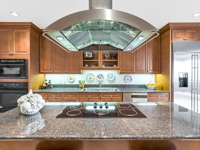 kitchen with island exhaust hood, appliances with stainless steel finishes, sink, and dark stone counters